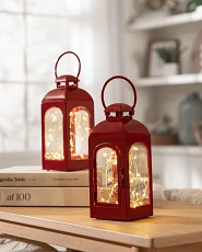 Pair of red fairy light lanterns on a wooden table